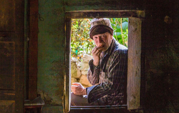 Persona mayor cerca de una ventana en una escena cotidiana.