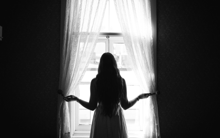 Silueta de una mujer cerca de una ventana interior.