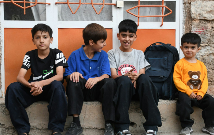 Cuatro jóvenes sentados juntos en escalones exteriores.