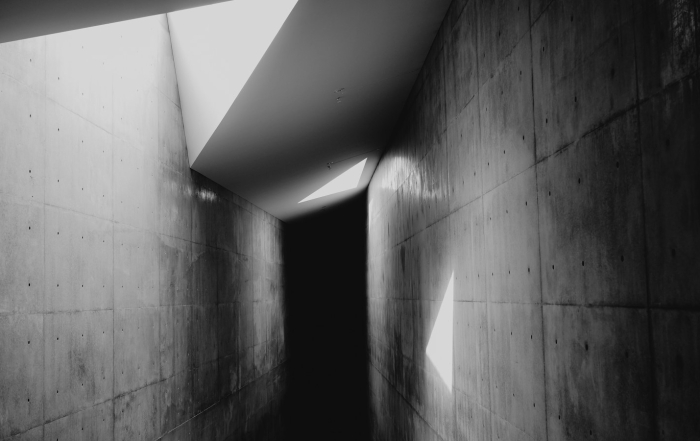 Pasillo arquitectónico vacío con luces y sombras marcadas.