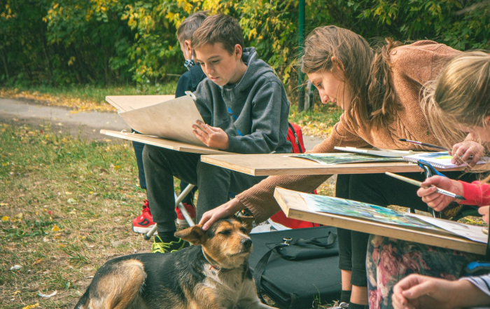 Clase de arte al aire libre con niños, guía y actividad creativa.