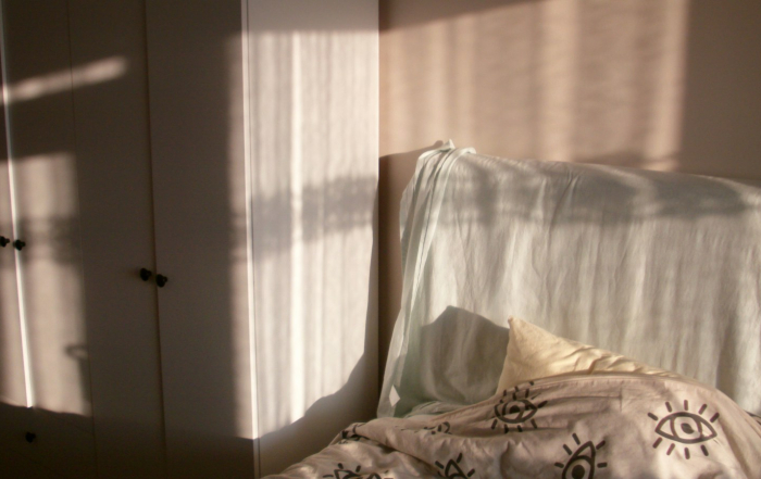 Luz matinal que ilumina una cama y un armario en un dormitorio real.